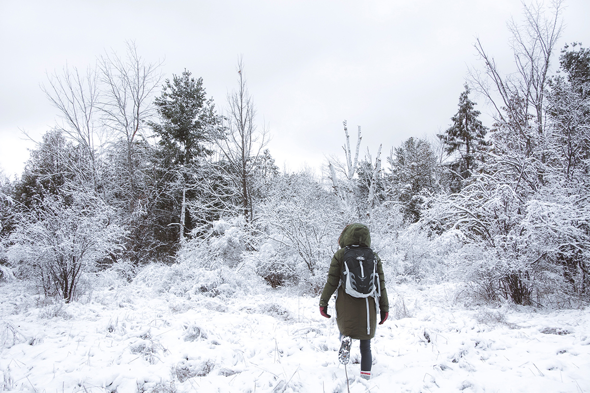 Woman is solo hiking through a winter forest in Ontario, Canada.