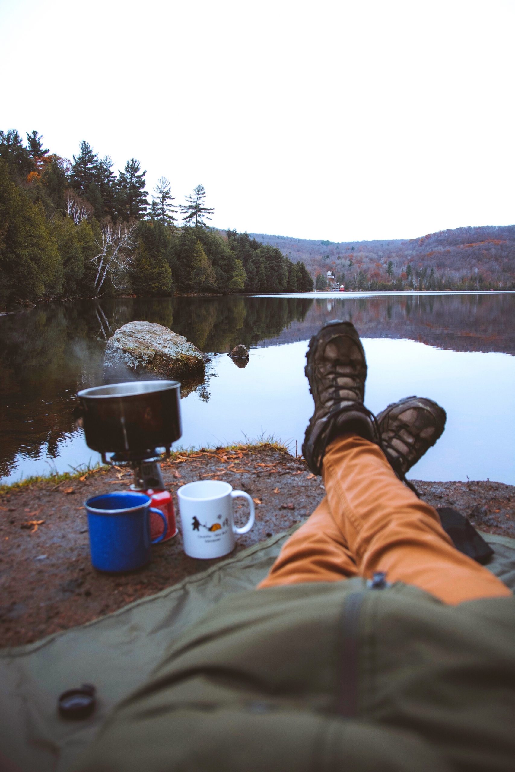 A woman sits waiting for water to boil for tea. It's important that we do dishes properly in the backcountry to prevent damage to our ecosystems and to avoid attracting animals.