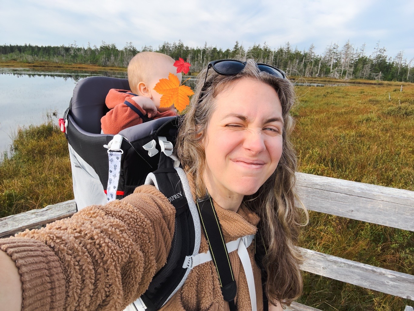 Woman with a baby in an osprey backpack hike on a trail.